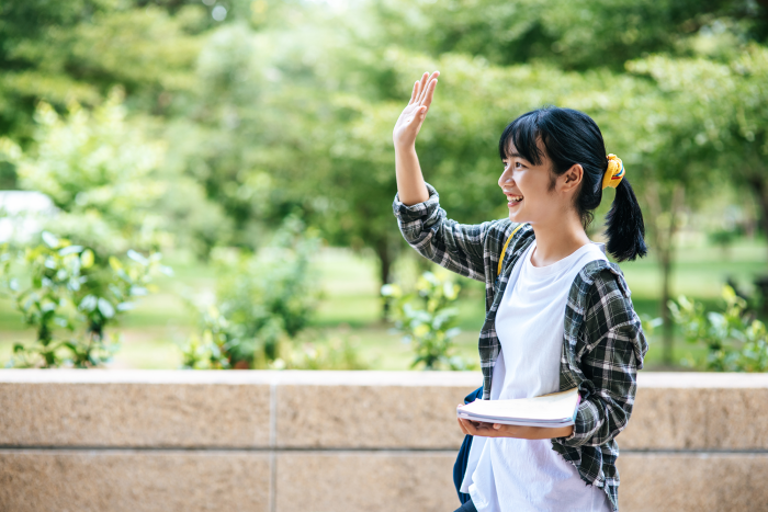 female-students-stand-stairs-hold-books